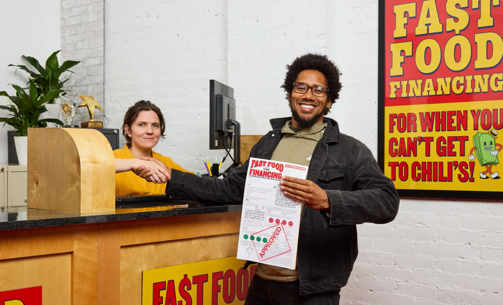 A Chili&#x27;s worker behind the counter shaking the hand of a customer participating in the chain&#x27;s &quot;Fast Food Financing&quot; campaign.