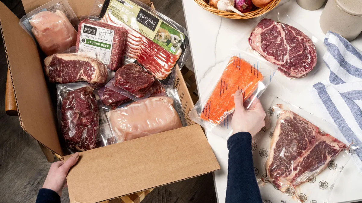A person opens a ButcherBox order and puts the meat on a table.